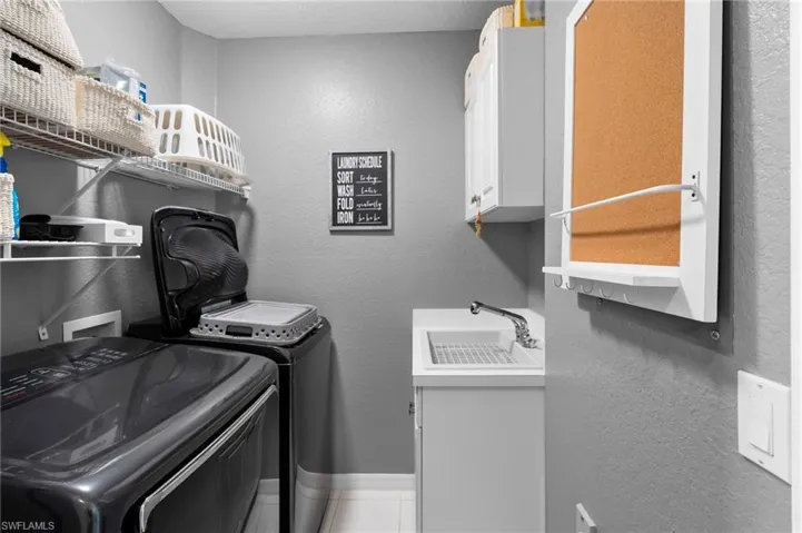 Dedicated laundry area featuring a utility sink with a chrome faucet, wall-mounted cabinetry, and built-in wire shelving