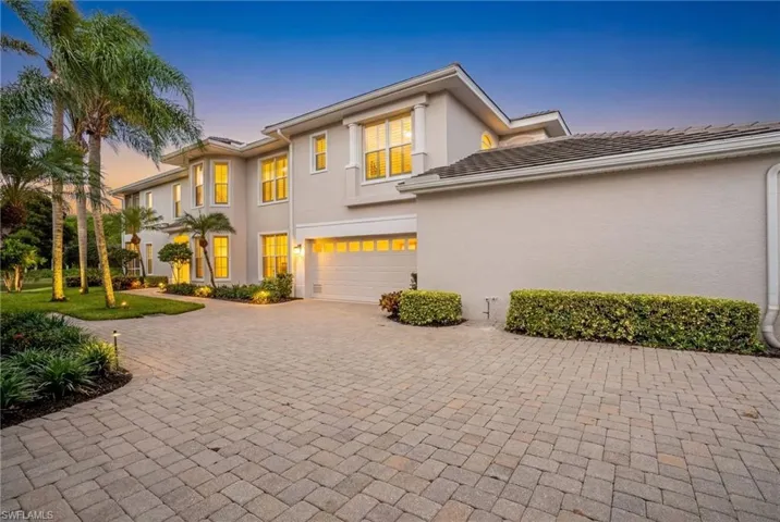 Stucco exterior with multiple windows, an attached two-car garage, and a paver driveway