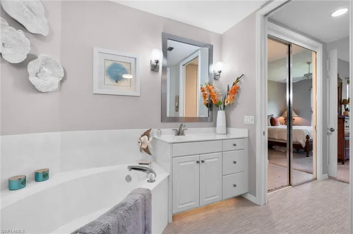 Bathroom featuring a built-in corner soaking tub, white vanity with an undermount sink, and a mirrored wall cabinet