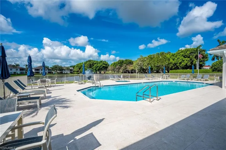 Outdoor swimming pool featuring a tiled interior, perimeter deck, and stainless steel access ladders