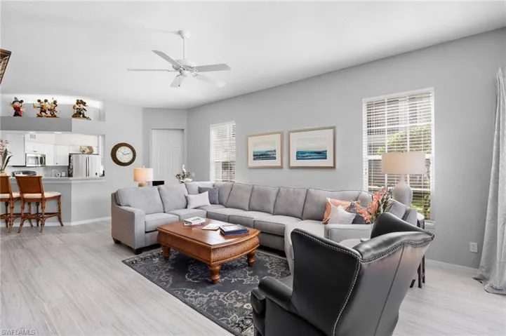Open concept living space featuring light wood-finish flooring, a ceiling fan, and two windows with blinds
