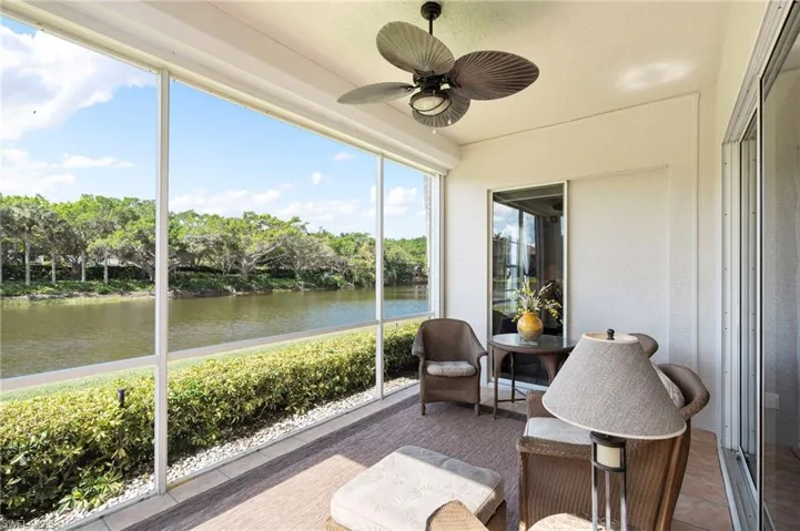 Screened patio featuring a ceiling fan, water frontage, surrounding foliage, and sliding glass doors