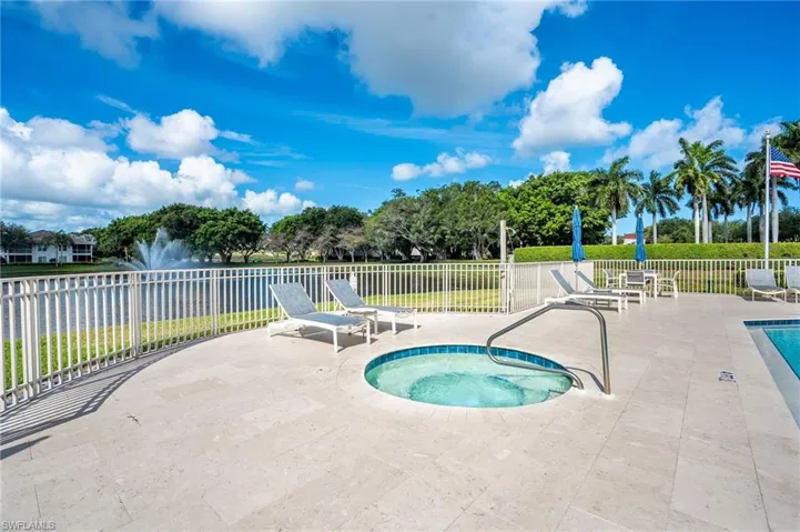 Outdoor spa with surrounding patio pavers, metal safety railing, and a white metal fence