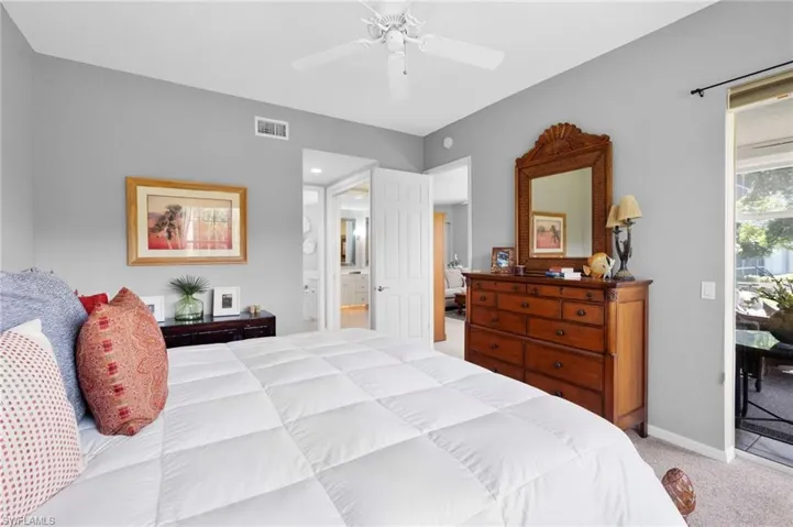 Main bedroom featuring light gray walls, a white ceiling fan, and a glass-paneled sliding door opening to an outdoor patio