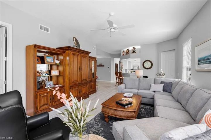 Spacious living area featuring light gray wall paint, wood-finish flooring, and a white ceiling fan