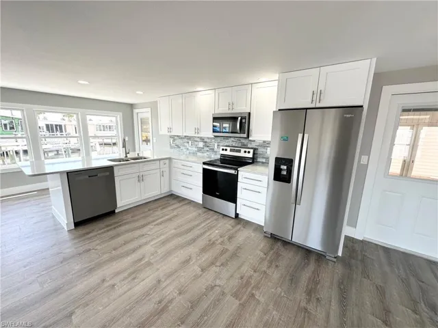 Kitchen featuring stainless steel appliances, hardwood / wood-style flooring, sink, and backsplash
