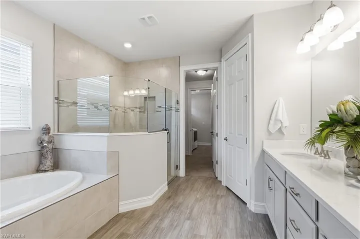 Ensuite, wood look tile floor, dual sinks, separate shower and soaking tub
