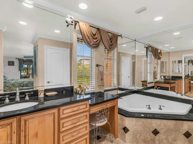 Bathroom with vanity, tiled bath, and ornamental molding