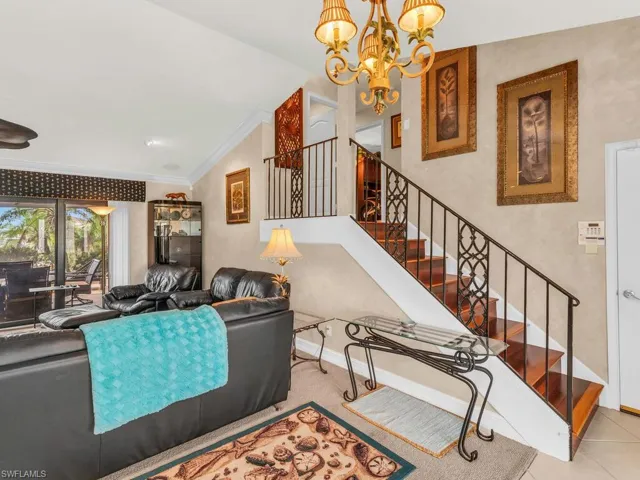 Tiled living room with an inviting chandelier, vaulted ceiling, and crown molding