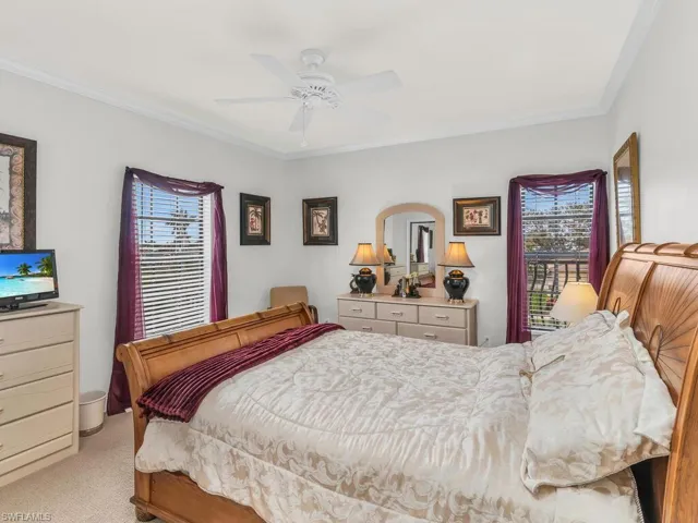 Bedroom featuring light colored carpet, multiple windows, ornamental molding, and ceiling fan