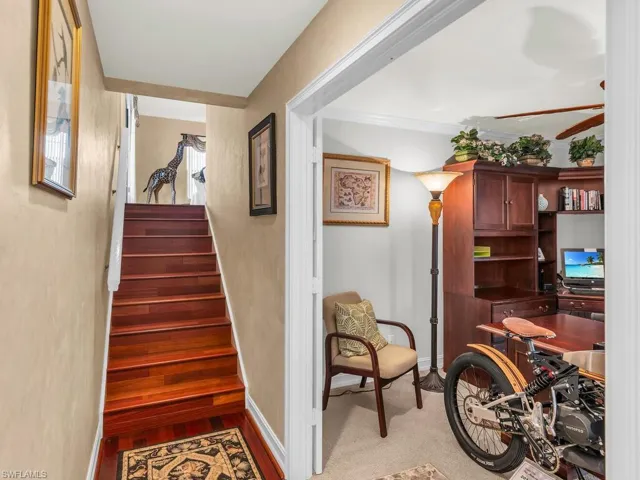 Staircase with ceiling fan, ornamental molding, and carpet floors