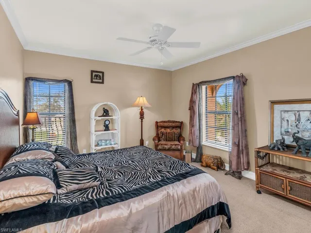 Carpeted bedroom featuring ceiling fan and ornamental molding