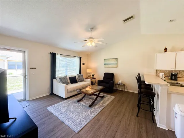 Living area with lofted ceiling, dark wood finished floors, a ceiling fan, and a textured ceiling