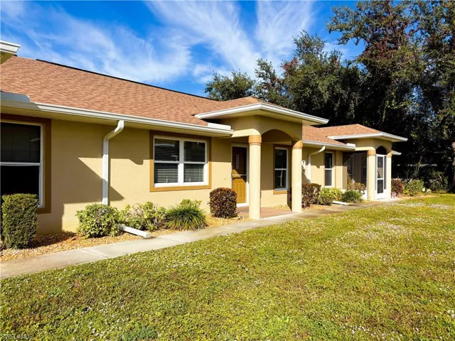 View of front of home with a front lawn, a shingled roof, and stucco siding