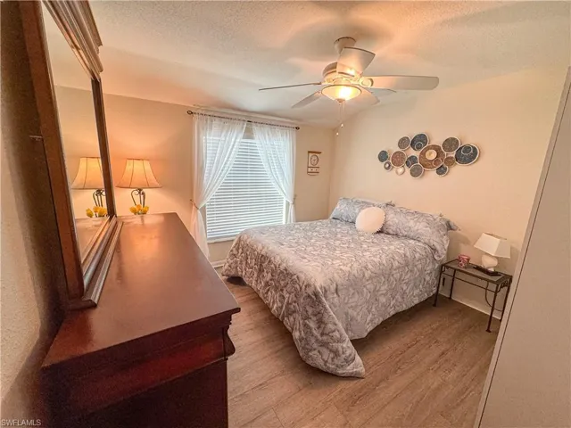 Bedroom with a textured ceiling, wood finished floors, and a ceiling fan