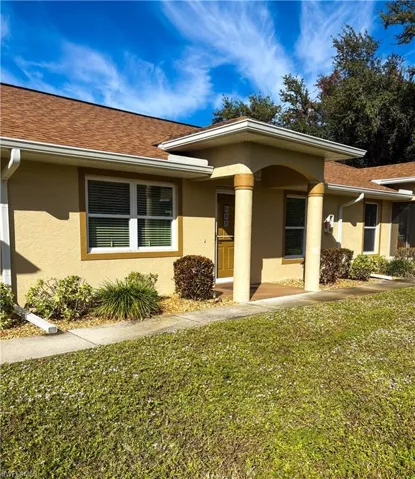 View of front of house featuring stucco siding, a front lawn, and a shingled roof