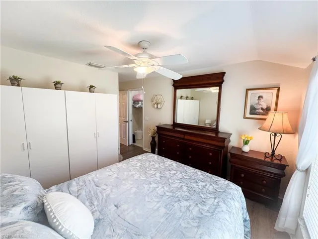 Bedroom with wood finished floors, ceiling fan, vaulted ceiling, and ensuite bathroom