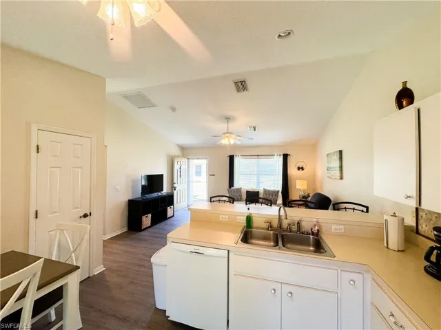 Kitchen with open floor plan, a peninsula, dishwasher, light countertops, and lofted ceiling
