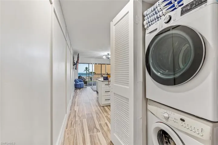 Washroom featuring stacked washer and dryer and light hardwood / wood-style flooring