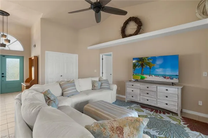 Tiled living room with ceiling fan and a towering ceiling
