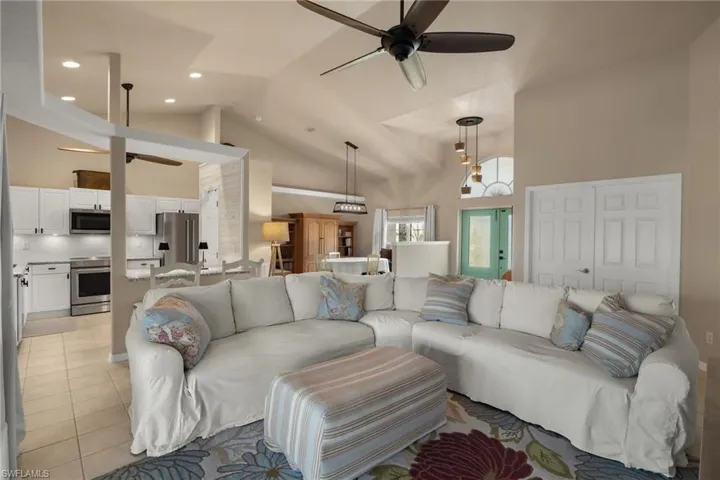 Living room with ceiling fan, light tile patterned floors, and high vaulted ceiling