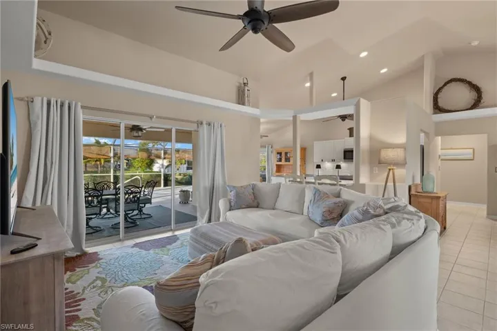 Living room with high vaulted ceiling, light tile patterned floors, and ceiling fan
