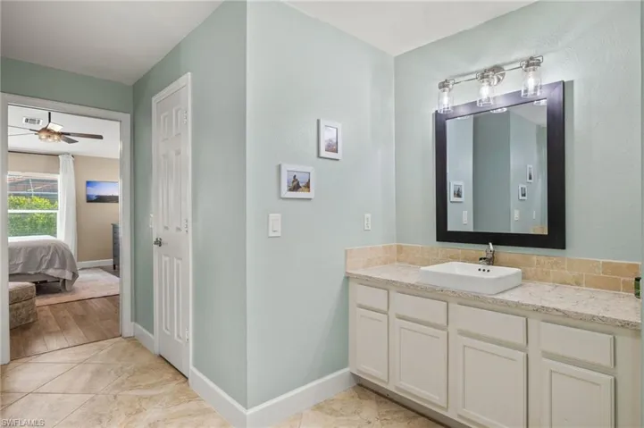 Ensuite bathroom featuring vanity, ceiling fan, and baseboards