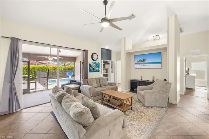 Living room with ceiling fan, light tile patterned floors, and vaulted ceiling