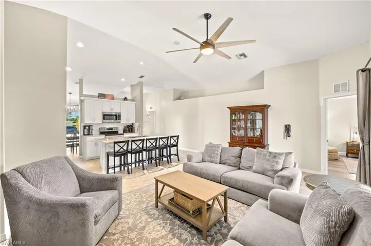 Living room with high vaulted ceiling, a ceiling fan, recessed lighting, and baseboards