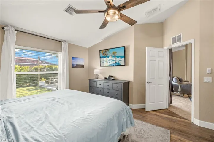 Bedroom with lofted ceiling, baseboards, wood finished floors, and a ceiling fan