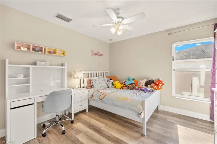 Bedroom with light wood-style floors, ceiling fan, baseboards, and a desk
