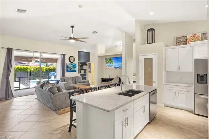 Kitchen with a sink, ceiling fan, appliances with stainless steel finishes, backsplash, and an island with sink