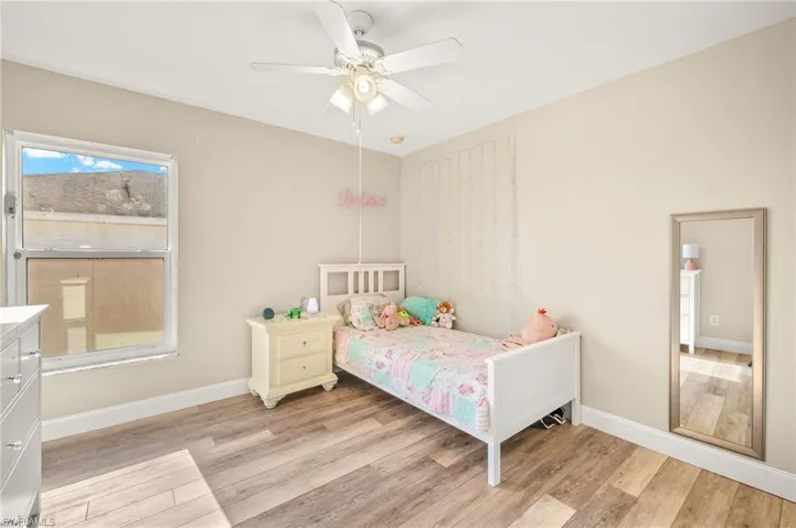 Bedroom featuring light wood finished floors, baseboards, and ceiling fan