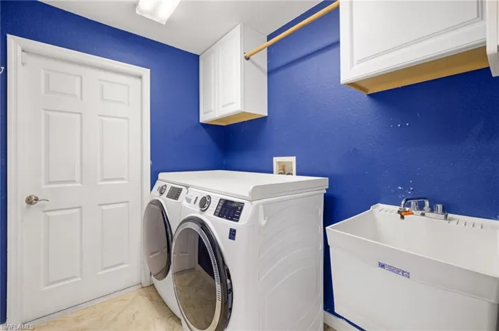 Laundry room featuring cabinet space, washer and dryer, a textured wall, and tile patterned floors