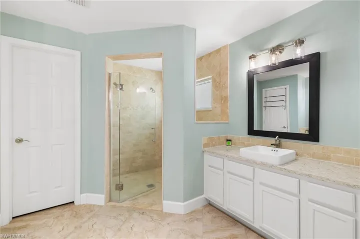 Bathroom featuring a shower stall, vanity, and baseboards