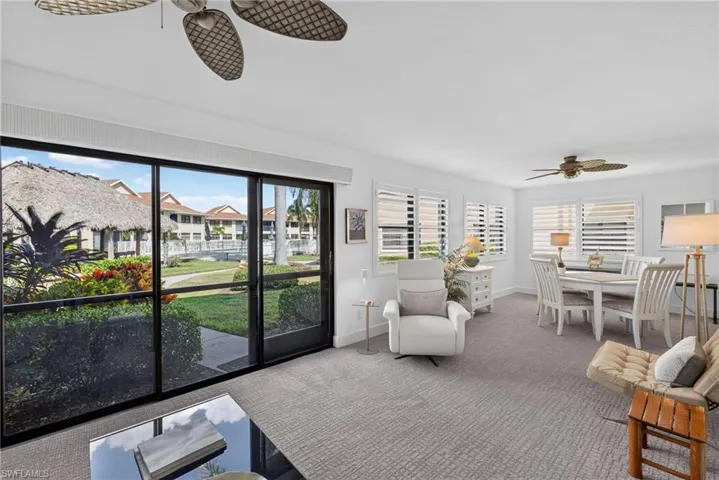 Living area featuring large sliding glass doors, neutral carpeting, plantation shutters, and ceiling fans