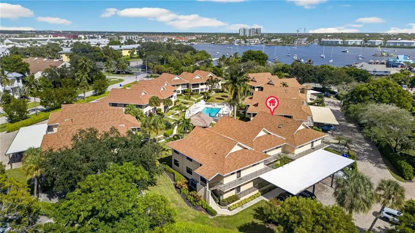 Multi-unit complex featuring shingle roofing, covered parking structures, and a central swimming pool