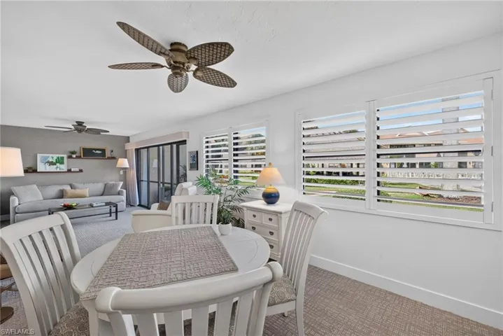 Interior space featuring plantation shutters, neutral carpeting, ceiling fans, and sliding glass doors