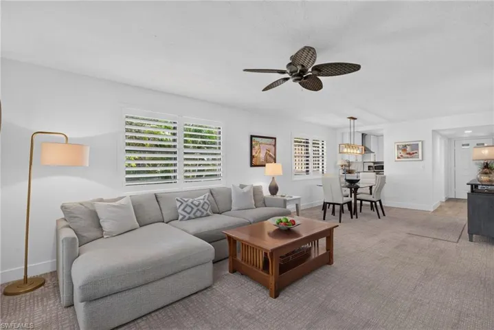 Open floor plan featuring carpeting, plantation shutters, a multi-blade ceiling fan, and recessed lighting