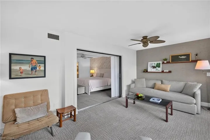 Neutral-toned carpet, textured accent wall, ceiling-mounted paddle fan, and sliding glass panel partition