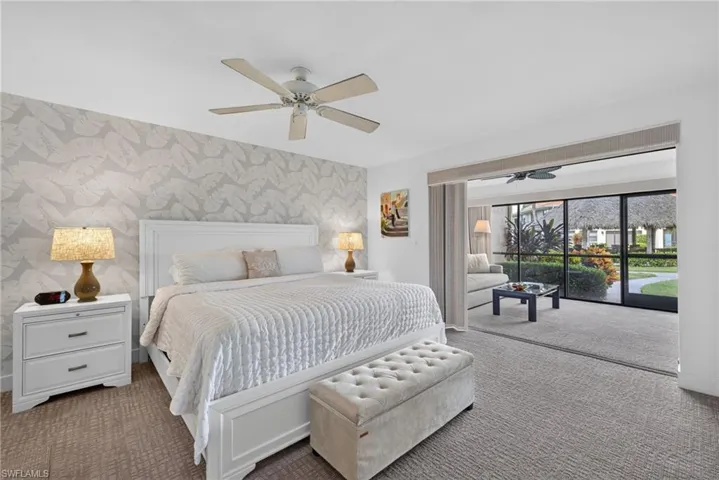 Room featuring patterned wallpaper, ceiling fan, and sliding glass doors leading to a screened enclosure