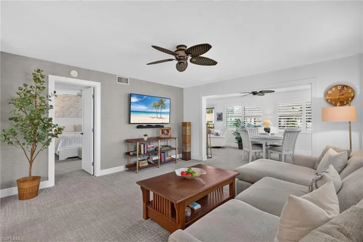 Neutral-toned textured wall treatment, ceiling-mounted paddle fans, and interior shutter window coverings