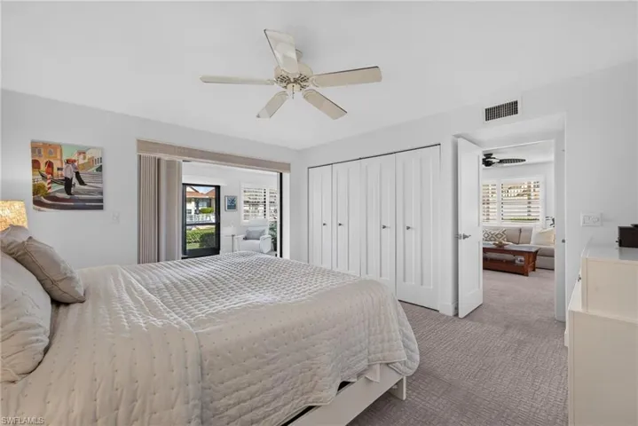 Bedroom featuring wall-to-wall carpeting, white built-in multi-panel closet doors, and a ceiling fan with integrated lighting