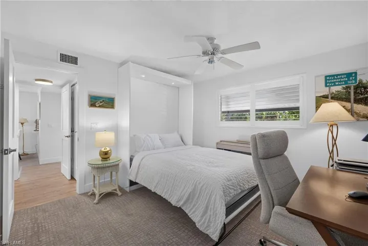 Built-in wall unit with integrated lighting, neutral carpeting, ceiling fan with light fixture, and horizontal window blinds