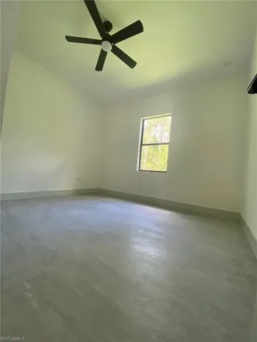 Unfurnished room with concrete flooring, ceiling fan, and baseboards