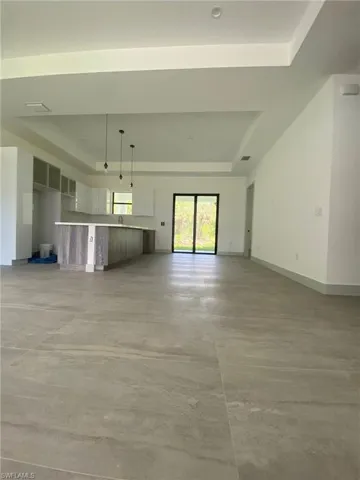Unfurnished living room featuring concrete flooring, baseboards, and a tray ceiling