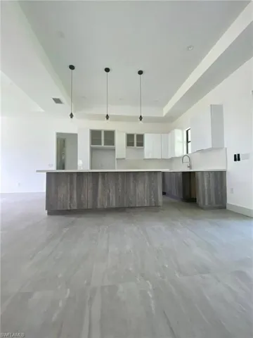 Modern Gourmet Kitchen:Bright and airy with sleek white cabinetry, a textured wood-look island, quartz countertops, and stylish pendant lighting under soaring tray ceilings. Perfect for casual dining and elegant entertaining.