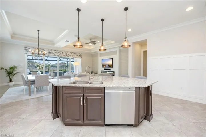 Kitchen features quartz counters, wainscoting panels, large island with a breakfast bar, recessed and pendant lighting