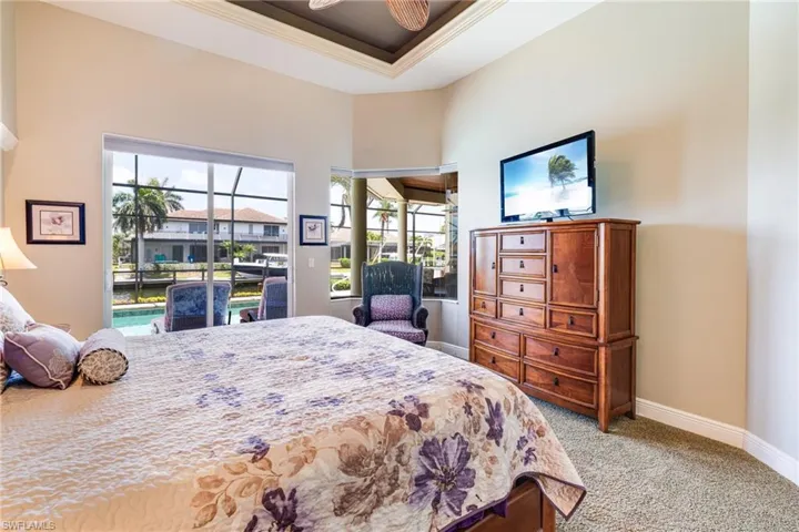 Bedroom featuring access to exterior, carpet floors, baseboards, ornamental molding, and a raised ceiling