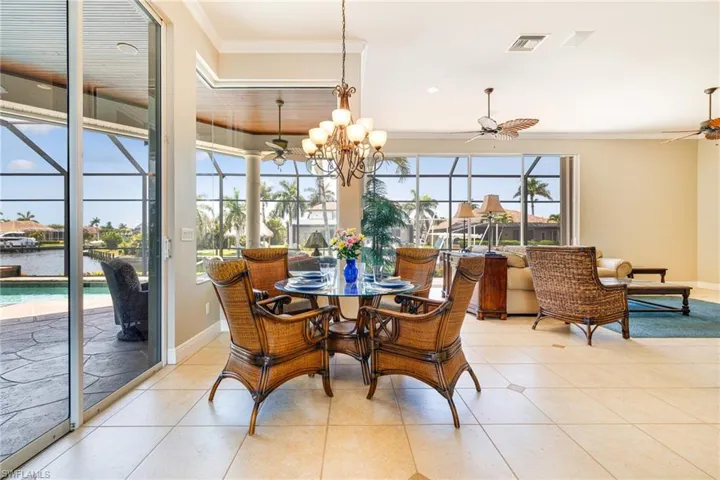 Tiled dining area featuring ceiling fan, crown molding, and baseboards